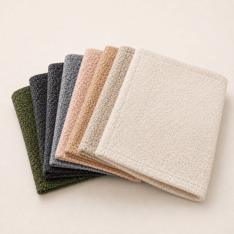 Stack of folded Bouclé bed runners in green, grey, beige and ivory shades