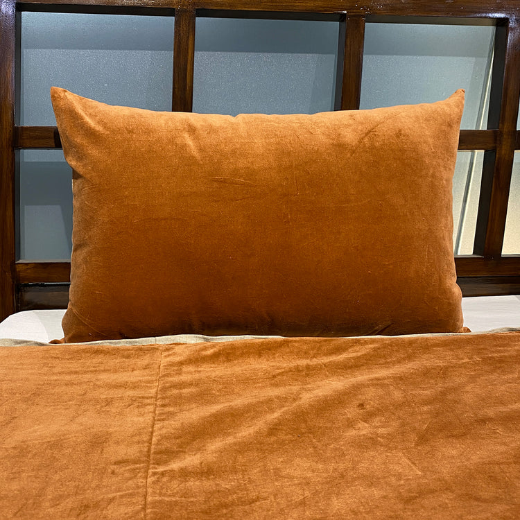 Terracotta velvet duvet cover draped over a bed corner