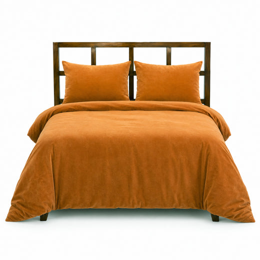 Terracotta velvet duvet cover and pillow shams styled on a made bed