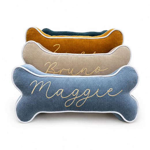 Personalized velvet dog bone pillow with custom embroidered name in gold thread