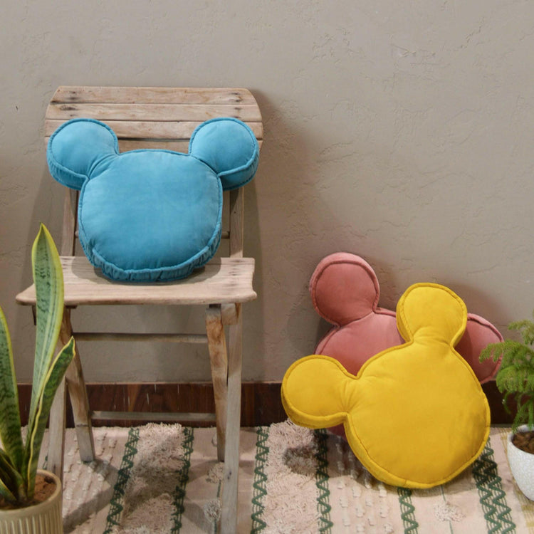 Blush pink velvet Mickey Mouse shaped cushion styled on a shelf