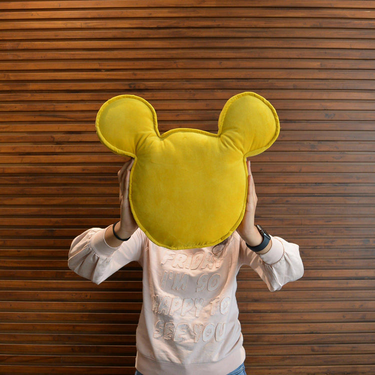 Child sitting with a mustard yellow velvet Mickey Mouse cushion